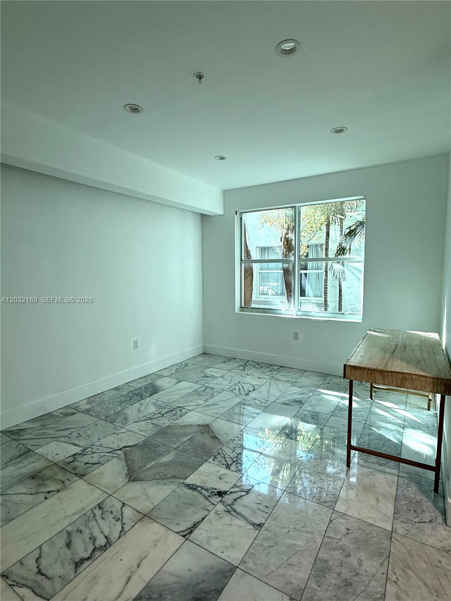 A room with white walls, recessed lighting, marble tile flooring, and a wooden desk — 1560 Drexel Ave # 103, Miami Beach FL 33139, MIAMI BEACH, FL