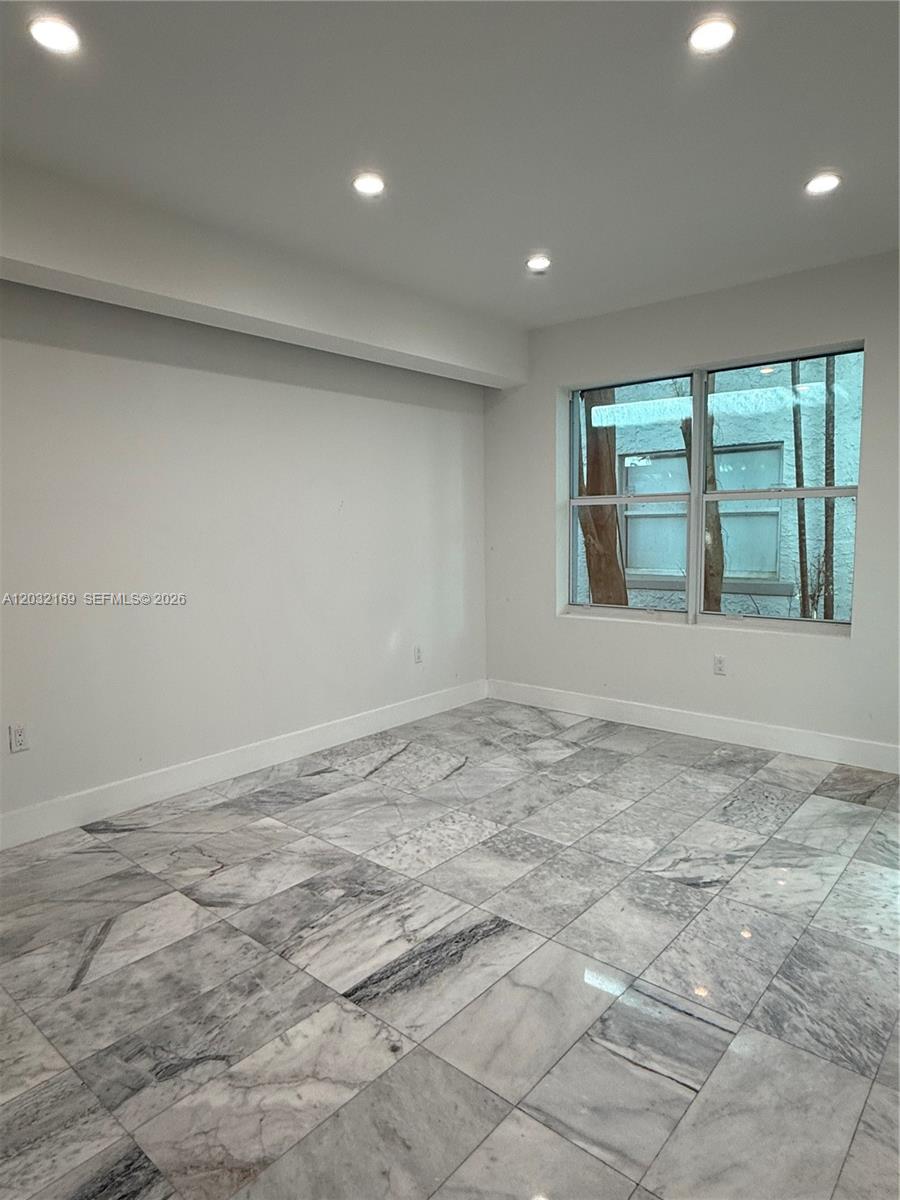 An empty room features white walls, recessed ceiling lights, and polished gray marble flooring — 1560 Drexel Ave # 103, Miami Beach FL 33139, MIAMI BEACH, FL