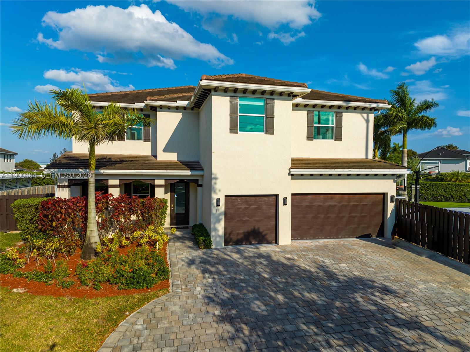 A two-story stucco house features a three-car garage, a paved driveway, and palm trees — 11 NW 122nd Ave, Miami FL 33182, MIAMI, FL