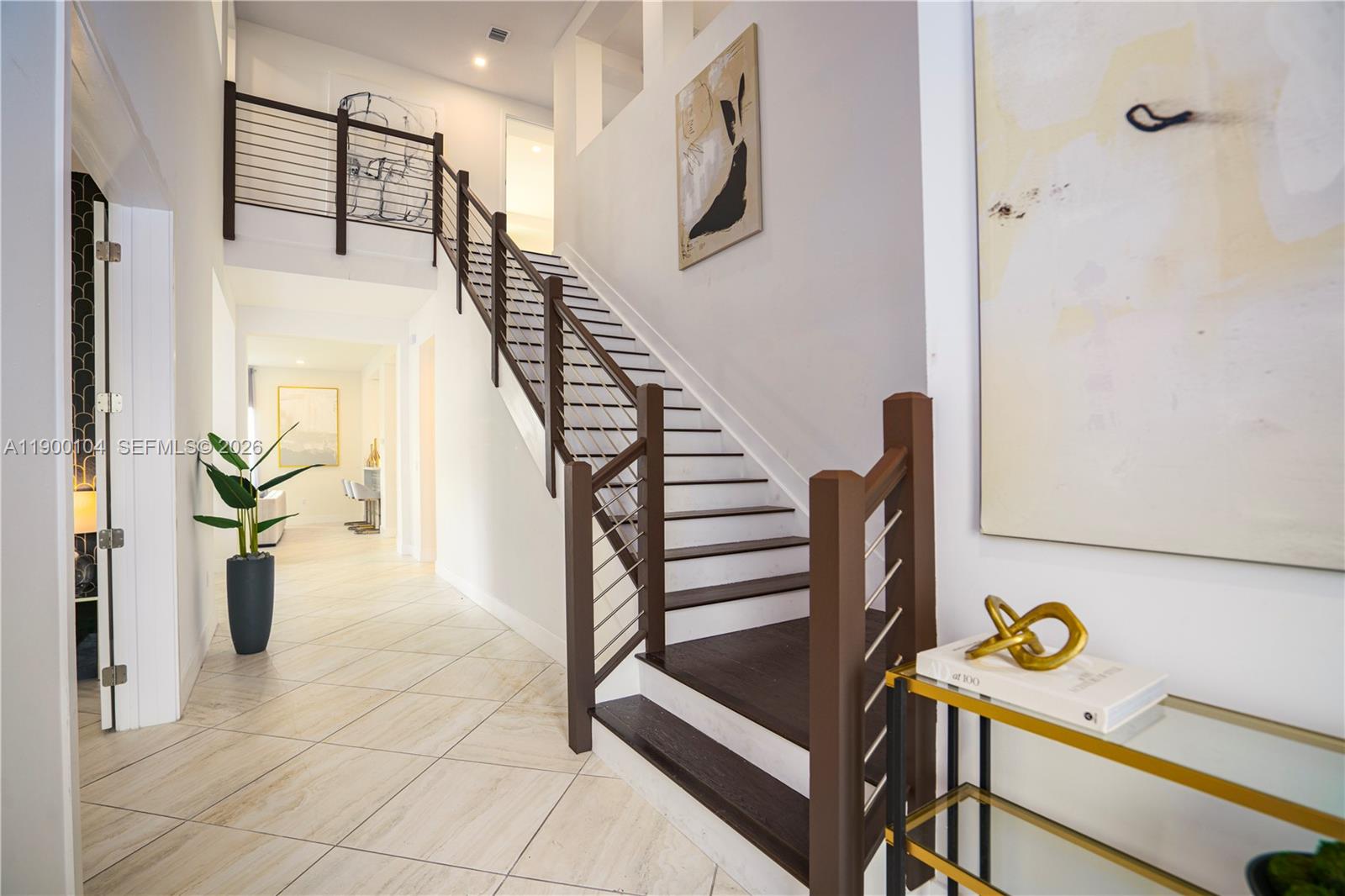 A modern staircase with dark wood treads and metal railings sits in a tiled foyer — 11 NW 122nd Ave, Miami FL 33182, MIAMI, FL