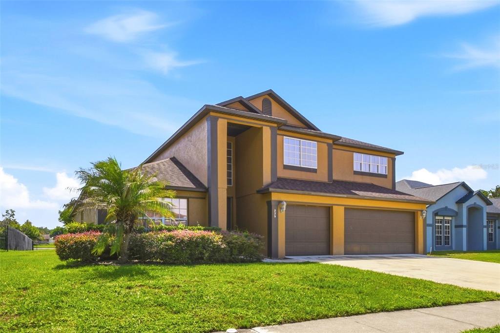 A two-story house with a tan stucco exterior, dark trim, and a two-car garage — 229 WHITESAND COURT, CASSELBERRY, FL