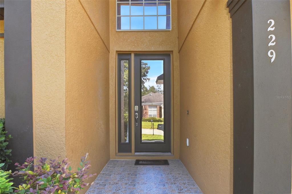 The front entrance features a dark door with a side light and a transom window — 229 WHITESAND COURT, CASSELBERRY, FL