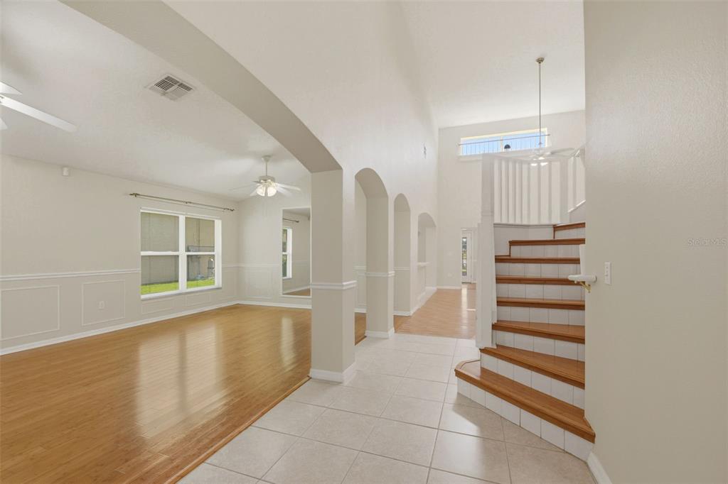 An interior view shows a tiled entryway, a wood-floored living area, and a staircase — 229 WHITESAND COURT, CASSELBERRY, FL