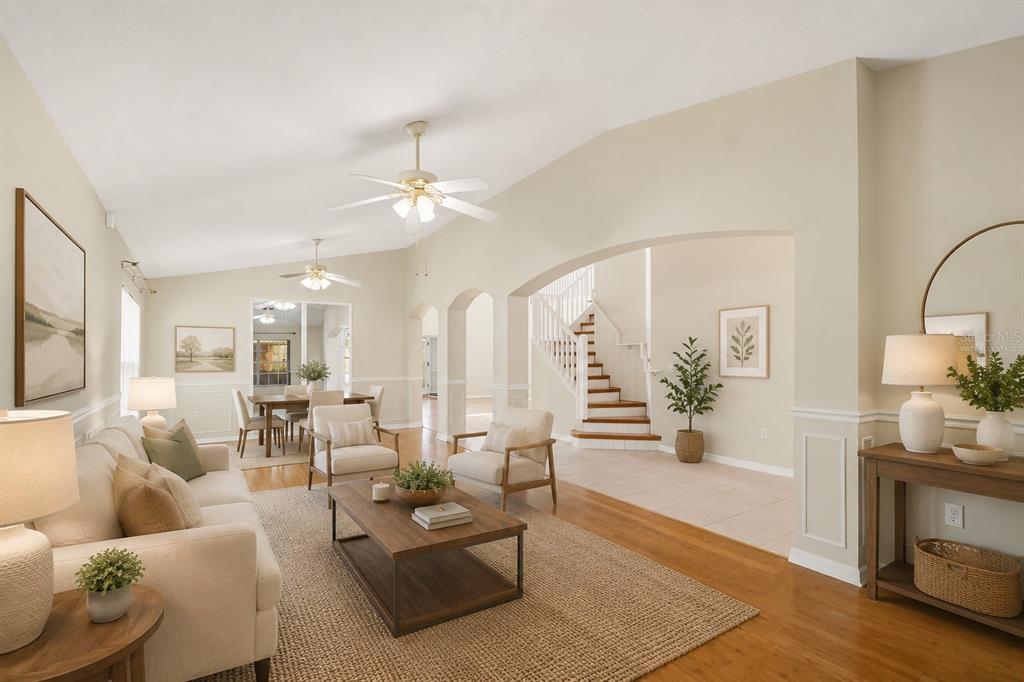 A living room with hardwood floors, a coffee table, and an arched entryway to stairs — 229 WHITESAND COURT, CASSELBERRY, FL