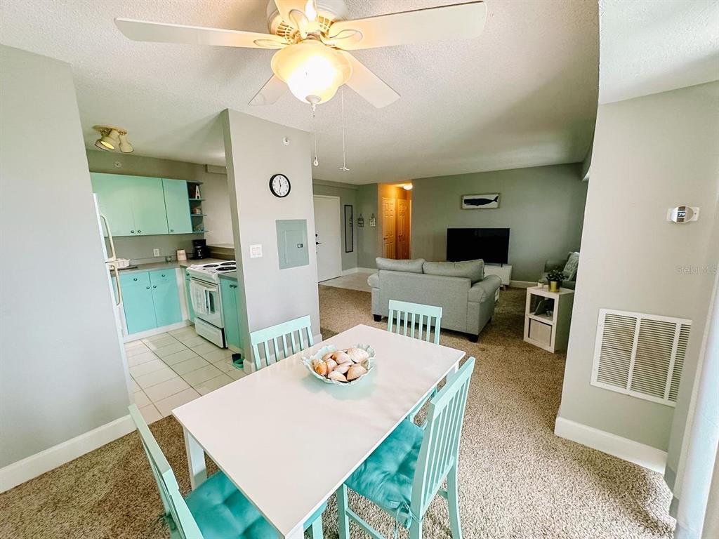 A dining area with a white table and teal chairs opens into a living room — 3315 58TH AVENUE S UNIT 414, ST PETERSBURG, FL