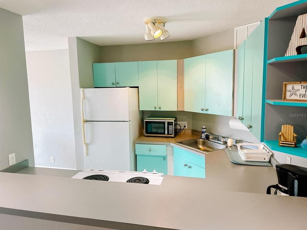 A kitchen features light blue cabinets, a white refrigerator, and a gray countertop — 3315 58TH AVENUE S UNIT 414, ST PETERSBURG, FL