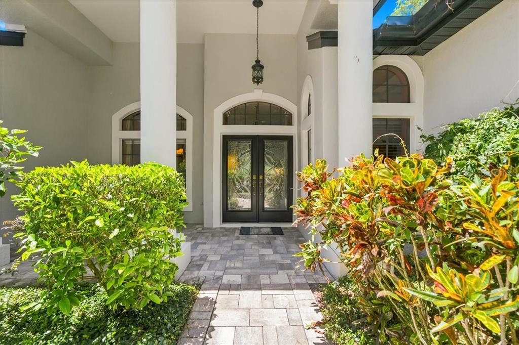 A paved walkway leads to a double-door entrance framed by two large white columns — 418 PINE BLUFF DRIVE, LUTZ, FL