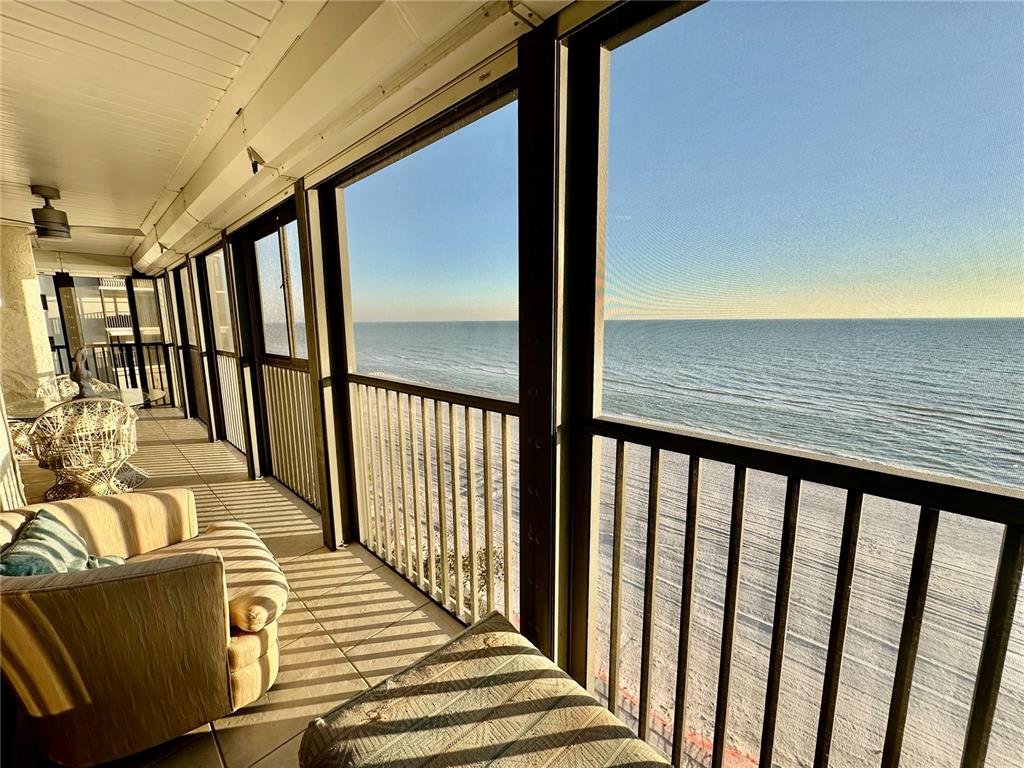 A screened-in balcony overlooks the ocean with tiled flooring and outdoor furniture — 15462 GULF BOULEVARD UNIT 501, MADEIRA BEACH, FL