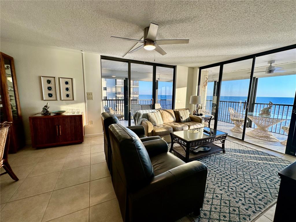 A living room features tile floors, a ceiling fan, and sliding glass doors overlooking the ocean — 15462 GULF BOULEVARD UNIT 501, MADEIRA BEACH, FL
