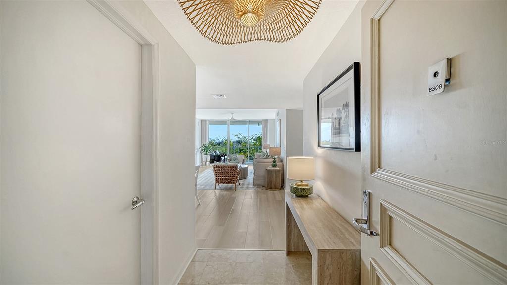 A bright entryway leads into a living area with light wood floors and balcony views — 1800 BENJAMIN FRANKLIN DRIVE UNIT B308, SARASOTA, FL