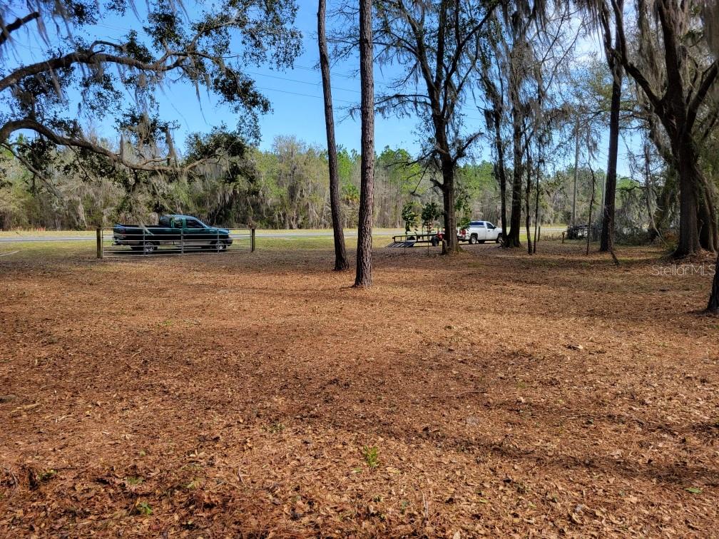 A wooded lot with a fenced area, a green truck, and a white pickup truck — 10133 SE HAWTHORNE ROAD, GAINESVILLE, FL