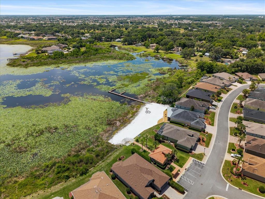 An aerial view shows a suburban neighborhood with houses bordering a lake and a dock — 5336 EDGEWATER WAY UNIT 5336, OXFORD, FL
