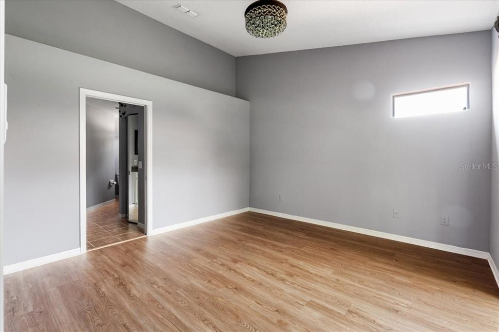 An empty room with gray walls, wood-look flooring, a vaulted ceiling, and a small window — 5336 EDGEWATER WAY UNIT 5336, OXFORD, FL