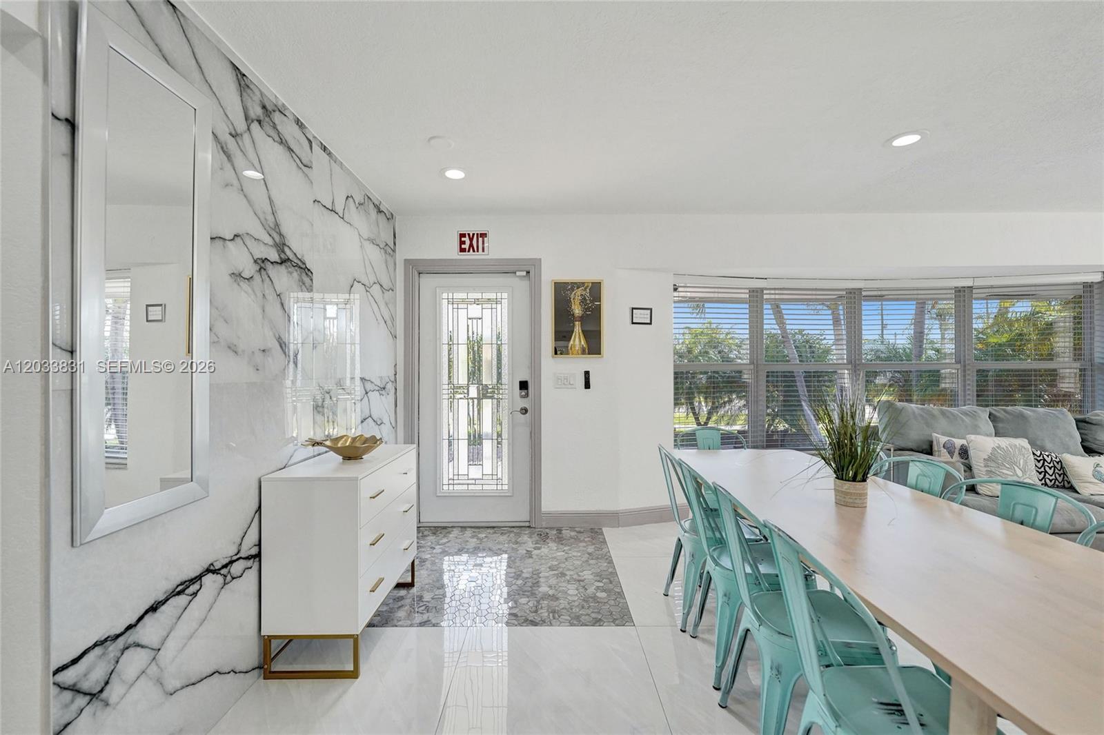 A dining area features a marble accent wall, white tile flooring, and light blue metal chairs — 218 SE 4th st # 0, Dania Beach FL 33004, DANIA BEACH, FL