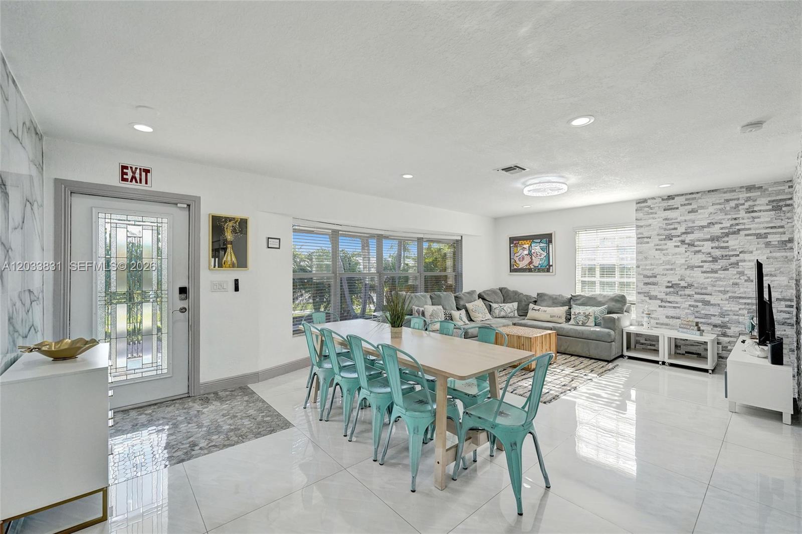 This open-concept living and dining area features white tile floors and a stone accent wall — 218 SE 4th st # 0, Dania Beach FL 33004, DANIA BEACH, FL