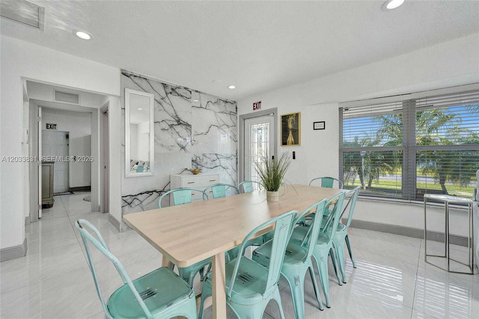 A dining room features a light wood table, turquoise metal chairs, and a marble accent wall — 218 SE 4th st # 0, Dania Beach FL 33004, DANIA BEACH, FL