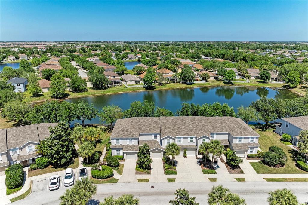 An aerial view shows a multi-unit townhouse complex situated beside a large community pond — 14830 SKIP JACK LOOP, LAKEWOOD RANCH, FL