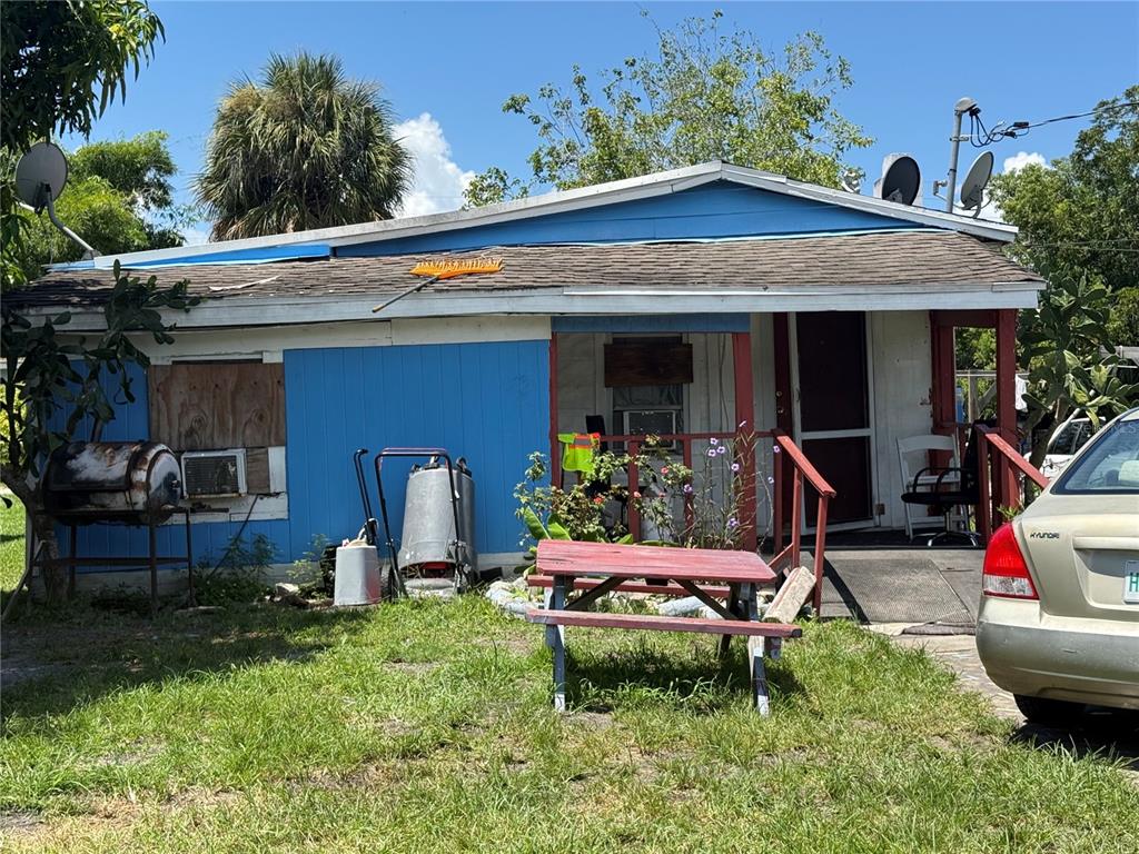 A small, blue, single-story house with a red picnic table and a parked car outside — 810 PERSON STREET, KISSIMMEE, FL
