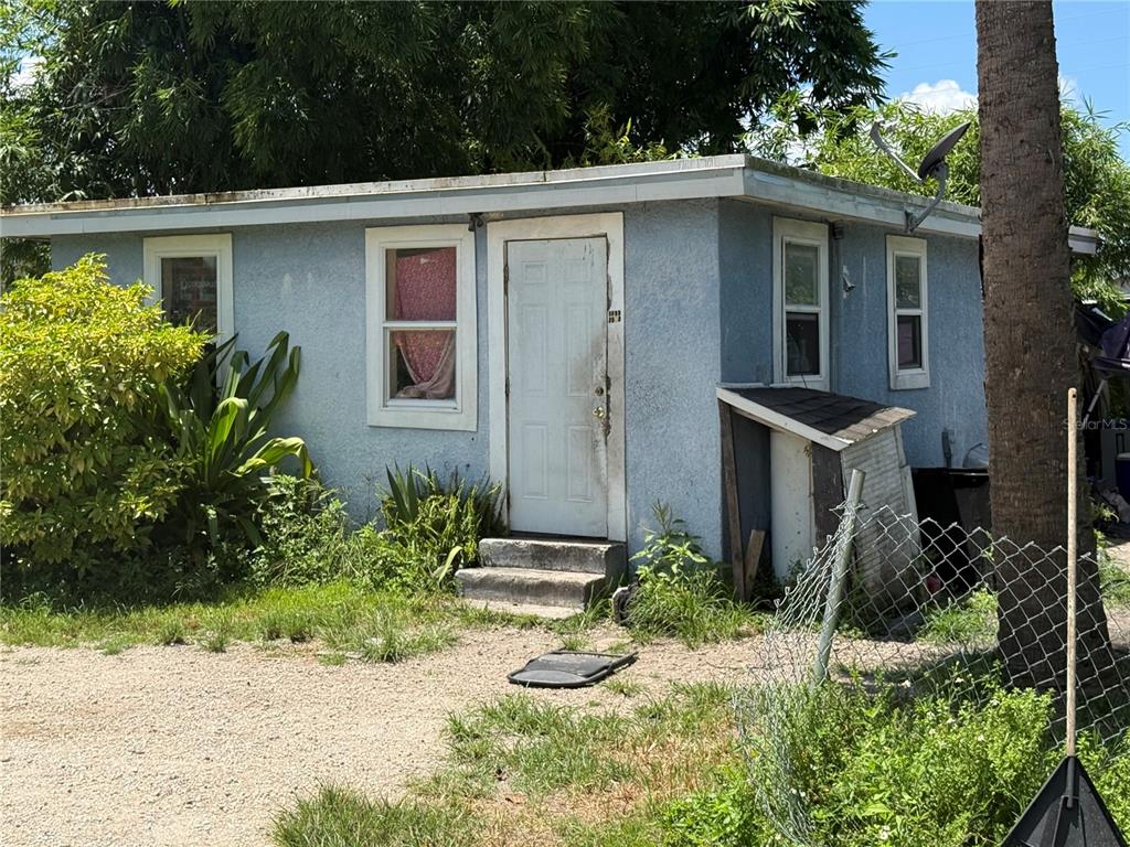 A small, light blue stucco house with a white door and a gravel yard — 810 PERSON STREET, KISSIMMEE, FL