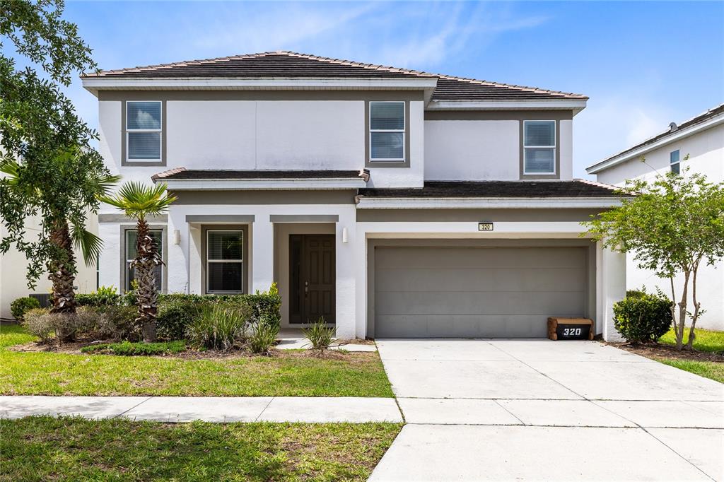 A two-story house with a white exterior, a two-car garage, and a front lawn — 320 BALLO DRIVE, KISSIMMEE, FL