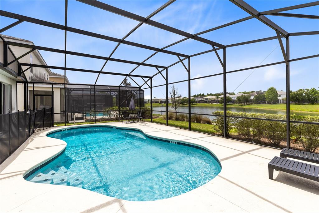 A screened-in swimming pool patio overlooks a lake behind a residential home — 320 BALLO DRIVE, KISSIMMEE, FL
