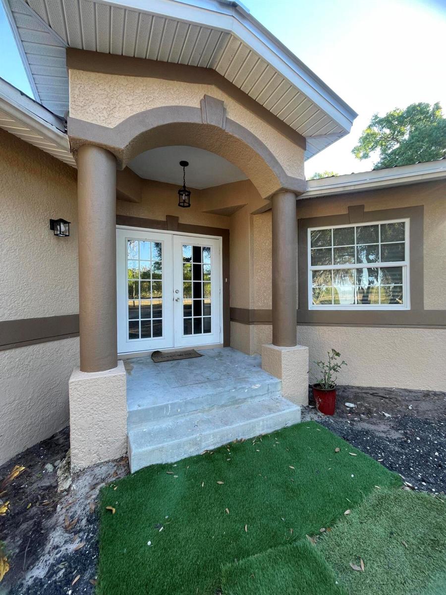 The exterior of a house features a covered entryway with two columns and double doors — 1220 A Road, FL 33935, FL