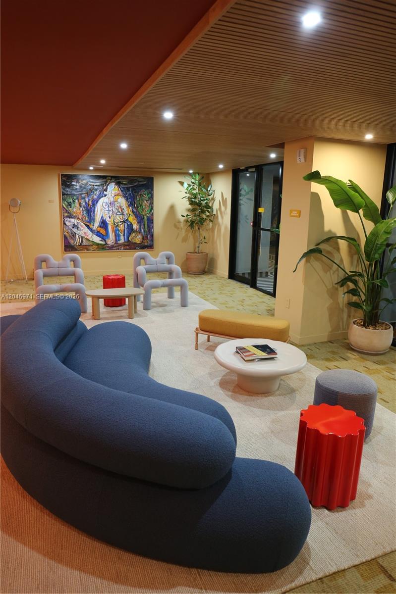 A modern lounge area features a curved blue sofa, colorful accent tables, and abstract artwork — 90 NE 32nd St # 702, Miami FL 33137, MIAMI, FL