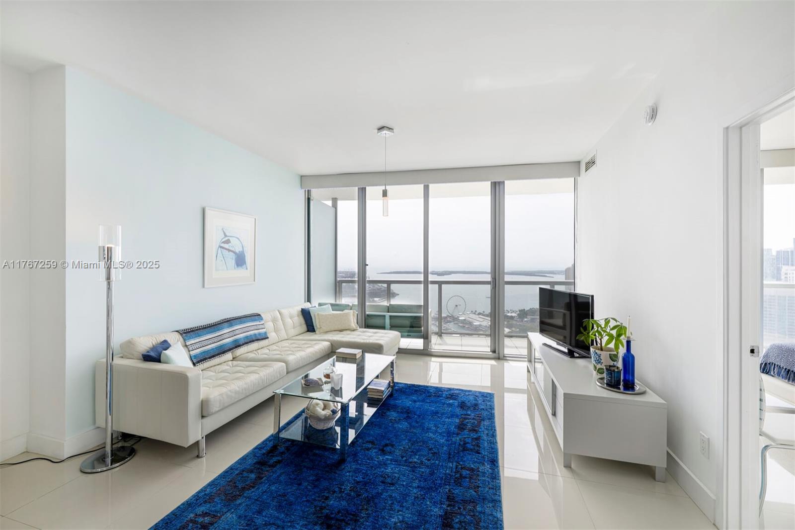 A living room features a white sectional sofa, a blue area rug, and floor-to-ceiling windows — 888 Biscayne Blvd # 4306, Miami FL 33132, MIAMI, FL