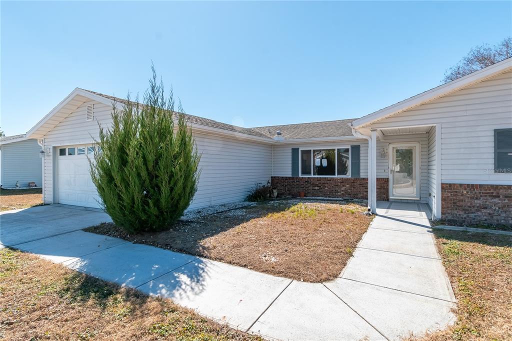 A single-story house with light gray siding and a brick facade sits on a lawn — 17952 SE 107TH COURT, SUMMERFIELD, FL