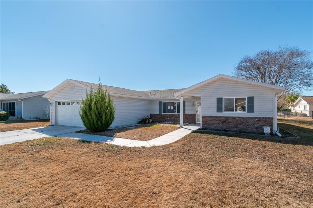 A single-story house with light gray siding, a brick base, and an attached garage — 17952 SE 107TH COURT, SUMMERFIELD, FL