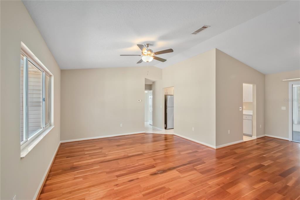 A spacious living room with hardwood floors, a ceiling fan, and neutral-colored walls — 17952 SE 107TH COURT, SUMMERFIELD, FL