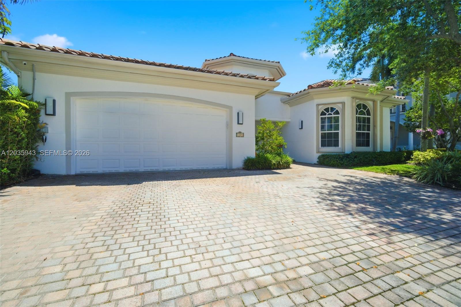 A white house with a two-car garage and a paved driveway under a blue sky — 1205 Seagull Ter, Hollywood FL 33019, HOLLYWOOD, FL
