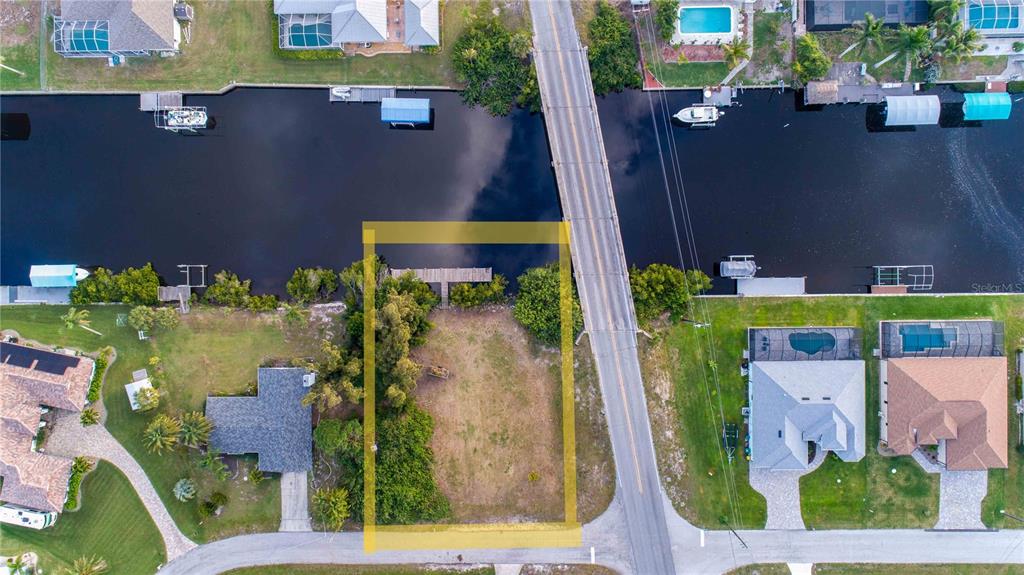 An aerial view shows a vacant waterfront lot highlighted by a yellow rectangle — 19379 MIDWAY BOULEVARD, PORT CHARLOTTE, FL