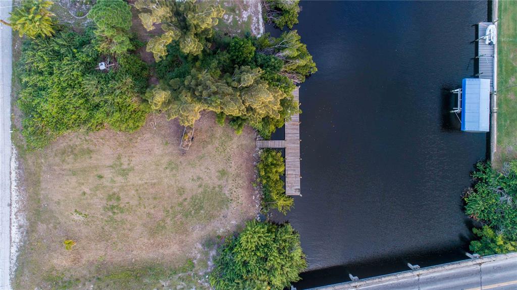 An aerial view shows a vacant waterfront lot with a wooden dock and boat lift — 19379 MIDWAY BOULEVARD, PORT CHARLOTTE, FL