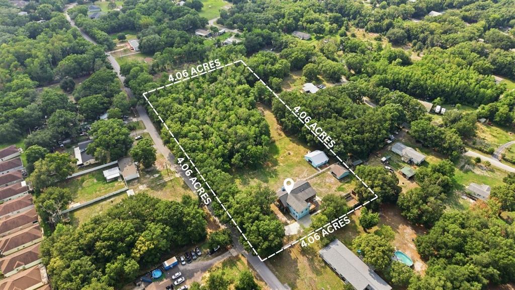 An aerial view shows a house on a large, wooded lot outlined in white — 26347 FOAMFLOWER BOULEVARD, WESLEY CHAPEL, FL