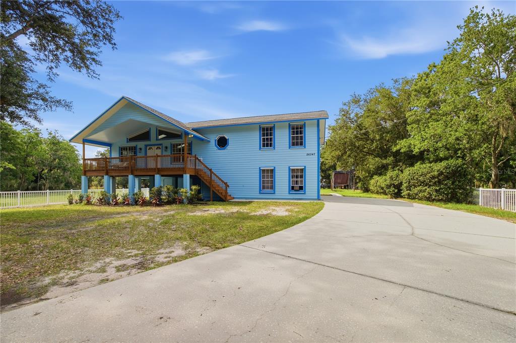 A light blue two-story house with a raised deck and a concrete driveway — 26347 FOAMFLOWER BOULEVARD, WESLEY CHAPEL, FL