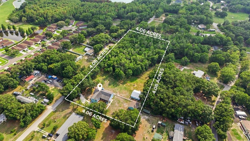 An aerial view shows a house and outbuilding on a 4.06-acre wooded lot — 26347 FOAMFLOWER BOULEVARD, WESLEY CHAPEL, FL