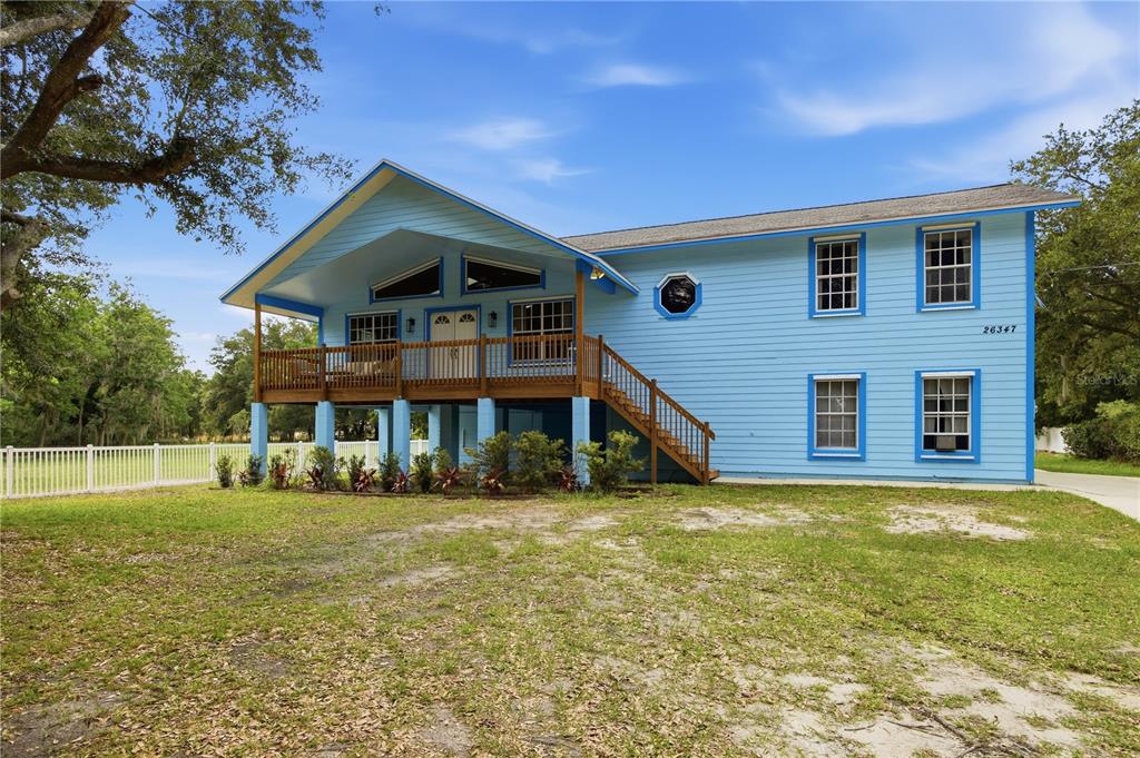 A two-story light blue house with a raised porch and wooden stairs — 26347 FOAMFLOWER BOULEVARD, WESLEY CHAPEL, FL