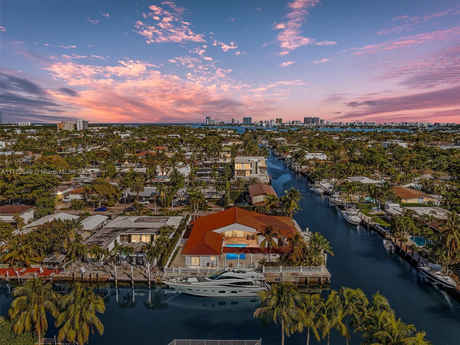 An aerial view shows a waterfront house with a red roof, pool, and docked yacht — 12904 Banyan Rd, North Miami FL 33181, NORTH MIAMI, FL