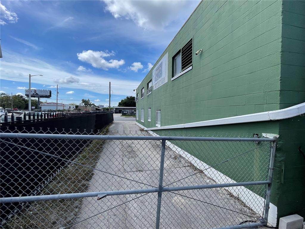 A view of a narrow paved alleyway running alongside a green concrete block building — 2909 OLD WINTER GARDEN ROAD, ORLANDO, FL