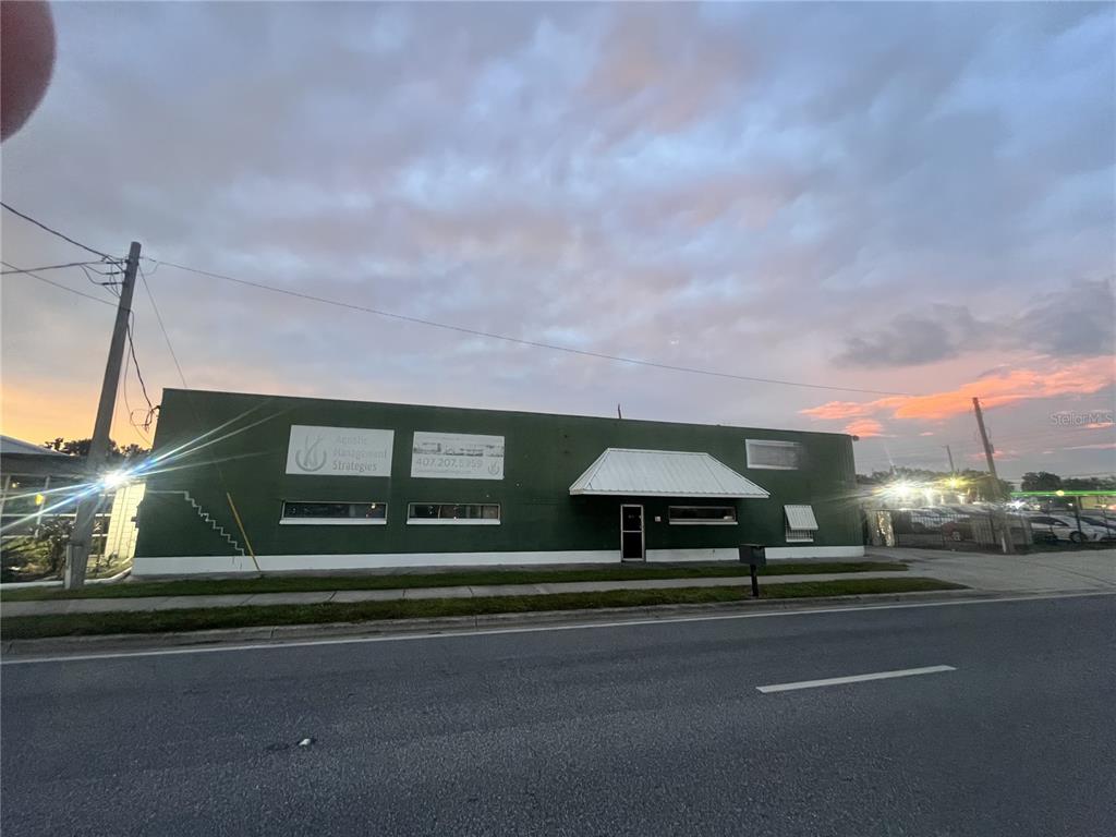 A green, single-story commercial building with a metal awning sits along a paved road — 2909 OLD WINTER GARDEN ROAD, ORLANDO, FL