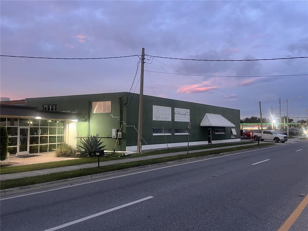 A green commercial building sits along a road under a cloudy sky at dusk — 2909 OLD WINTER GARDEN ROAD, ORLANDO, FL