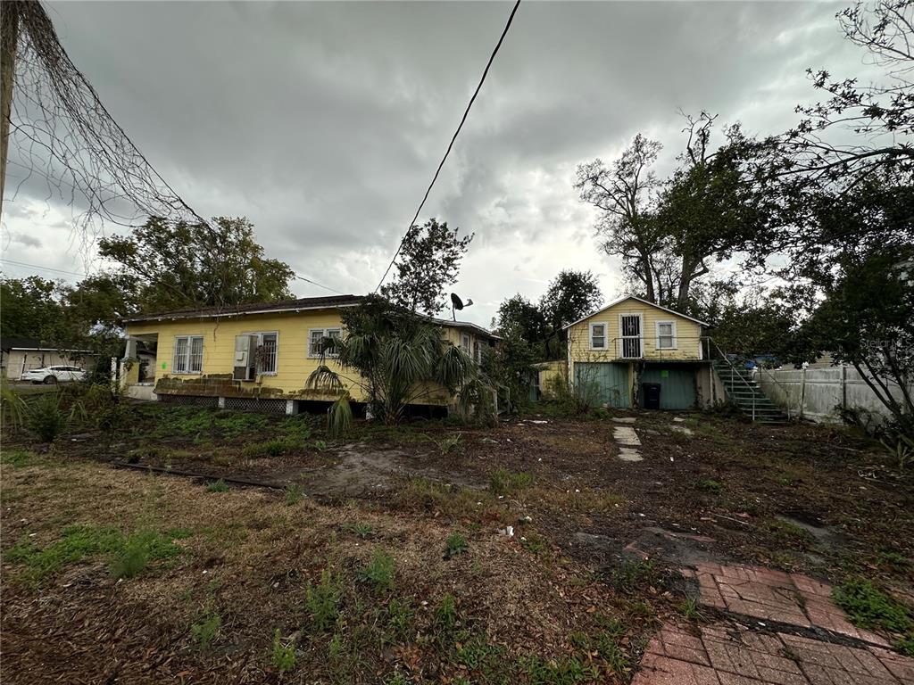 A yellow house and a detached two-story garage sit on a large, overgrown lot — 3210 N TAMPA STREET, TAMPA, FL