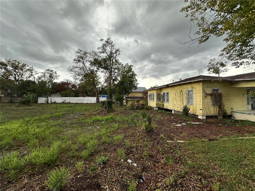 A yellow house with a large, overgrown yard under a cloudy sky — 3210 N TAMPA STREET, TAMPA, FL