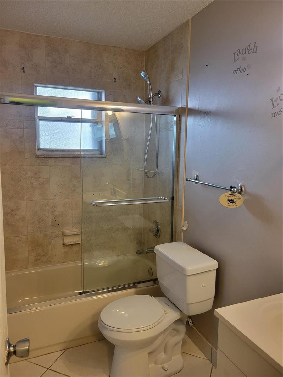 A bathroom features a tiled tub-shower combination, a white toilet, and a vanity — 1170 NW 90th Avenue, Plantation FL 33322, PLANTATION, FL