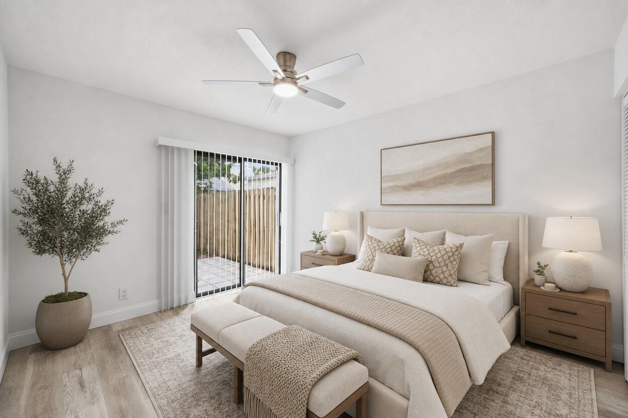 A neutral-toned bedroom features a bed, ceiling fan, sliding glass door, and a potted tree — 905 NW 22nd Avenue, Delray Beach FL 33445, DELRAY BEACH, FL