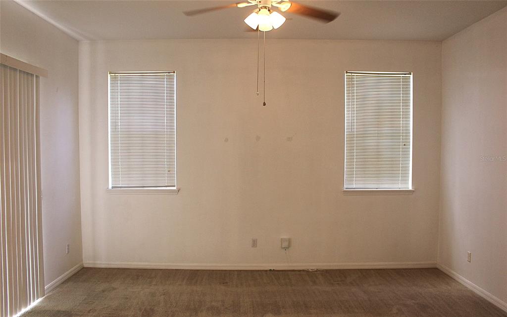 A carpeted living room features two windows with blinds and a ceiling fan — 771 MOUNTAIN ASH, DELTONA, FL