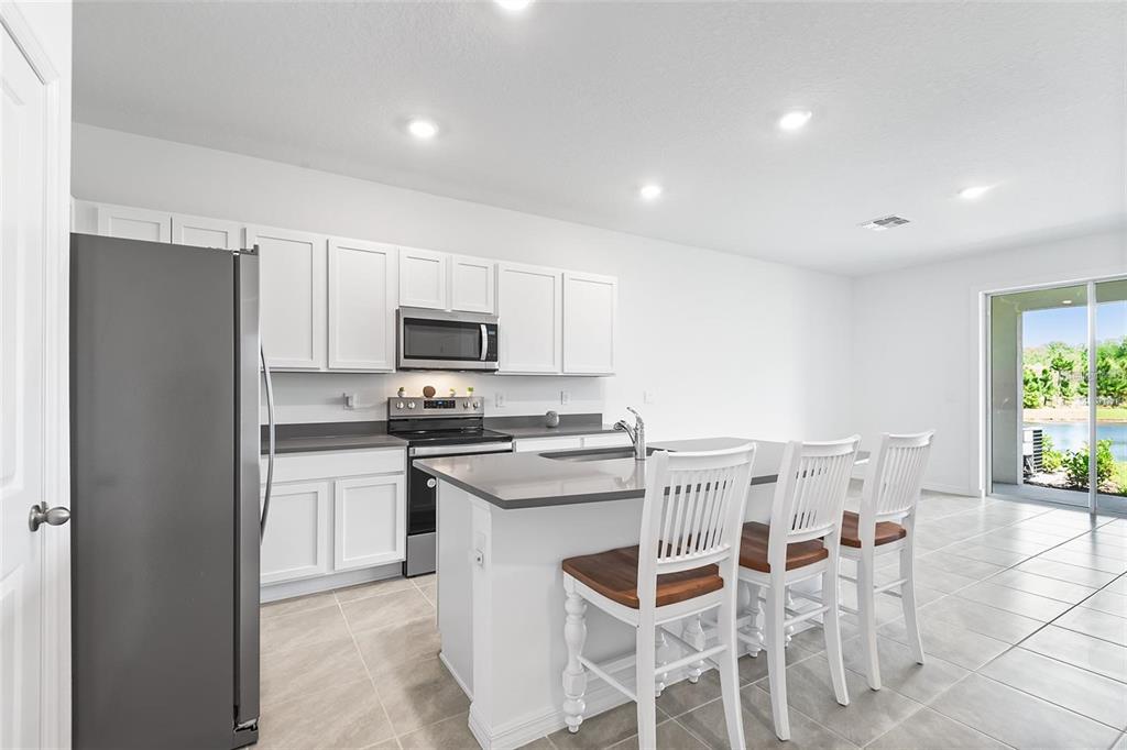 A kitchen features white cabinets, gray countertops, stainless steel appliances, and a central island — 11236 CRESCENT DEER DRIVE, LAND O LAKES, FL