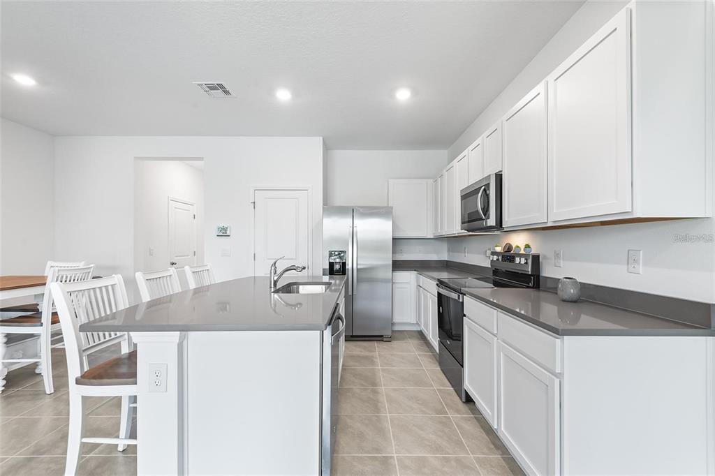 A kitchen with white cabinets, gray countertops, stainless steel appliances, and a central island — 11236 CRESCENT DEER DRIVE, LAND O LAKES, FL