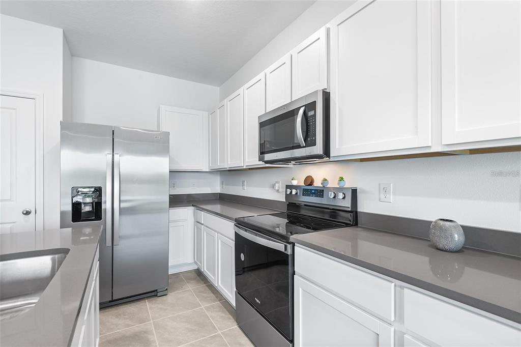 A kitchen featuring white cabinets, stainless steel appliances, and gray countertops — 11236 CRESCENT DEER DRIVE, LAND O LAKES, FL